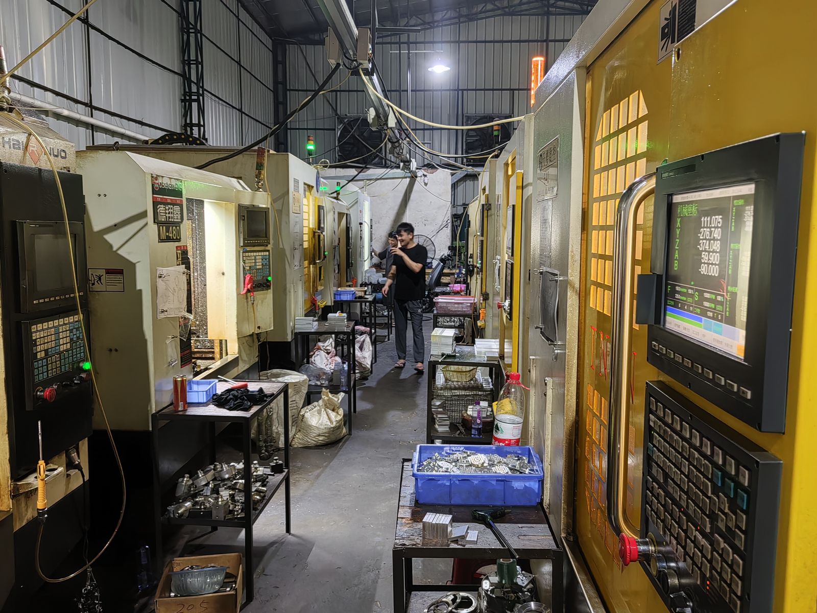 Two rows of CNC machining centers with an operator at work
